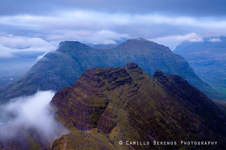 A persistent cloud is hugging the steep northern side of the Horns on Beinn Alligin after the warm evening light has given way to the blue hour. Beinn Dearg, a hill with Corbett status, rises steeply from the glen just behind the Horns.