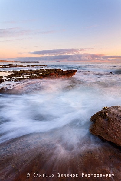 Strong currents are formed when the waves are funneled through this narrow chute in between rocks at Tyninghame beach, East Lothian. As the sun had just risen, the light was beautifully soft and warm.